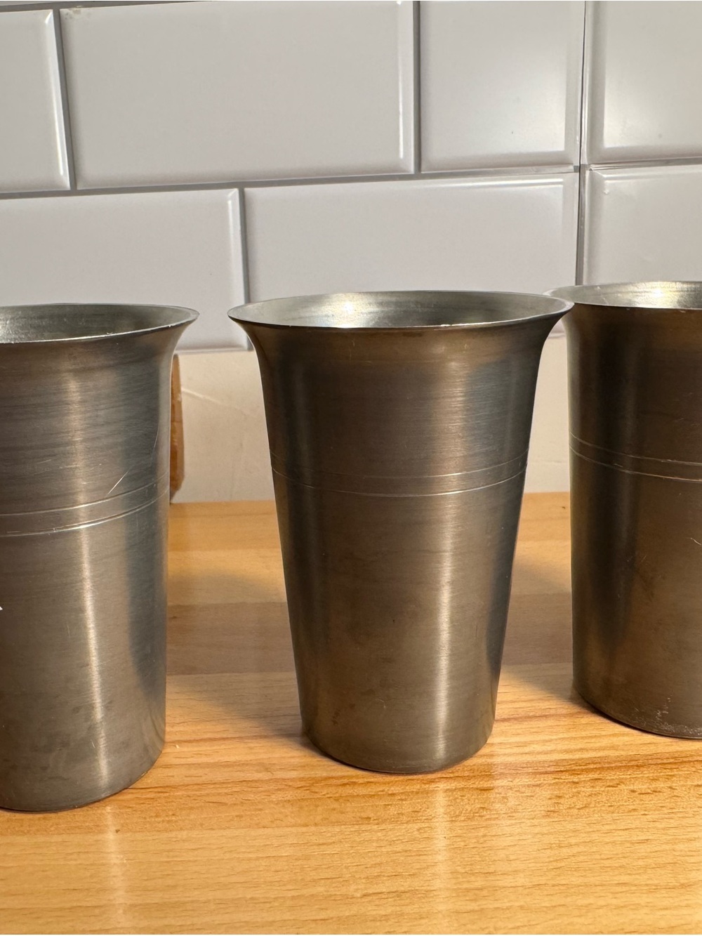A set of three vintage German pewter tumblers with incised bands.
